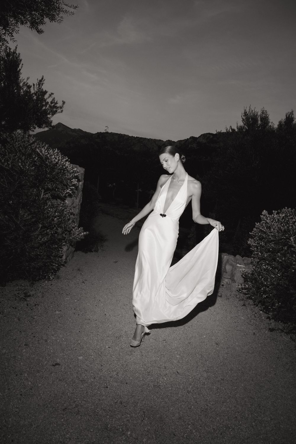 A figure in flowing white fabric appears to float mysteriously above a dark path in a series of black and white photos.