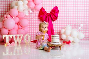 Pink and white balloon arch with a large red bow decorates a festive two-year birthday celebration setup with cake. NJ Cake Smash Photograph