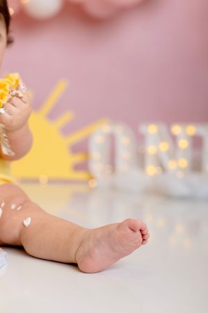 Close-up of baby's bare foot against blurred pink and yellow background with bokeh lights.