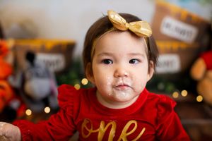 First birthday portrait with Winnie the Pooh themed decorations and gold bow accessory.