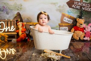 Whimsical bath time photo with Winnie the Pooh themed backdrop and white tub prop.