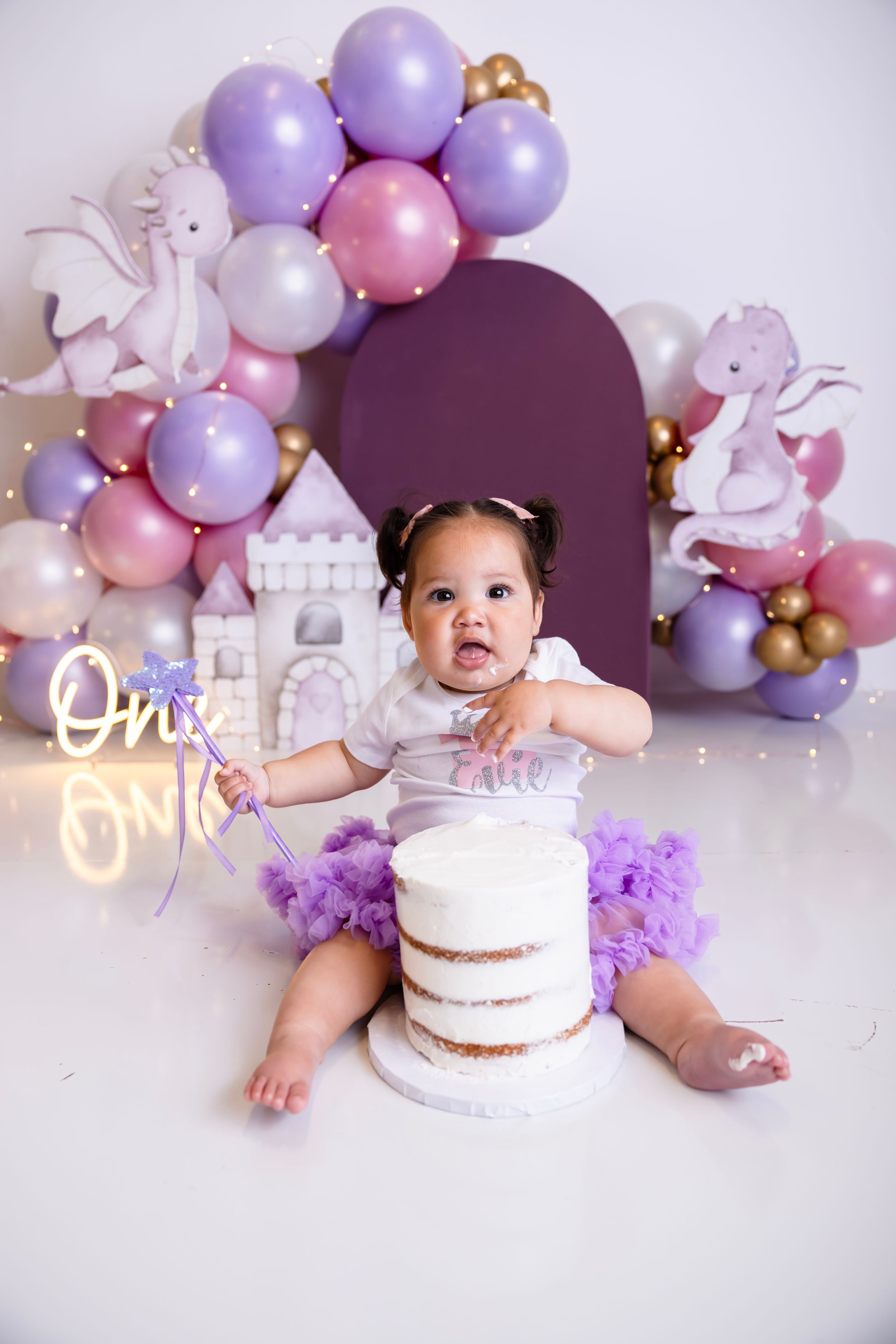 Baby girl in purple tutu sits with white smash cake. NJ photography studio located in Sussex County NJ. Cake Smash Photographer