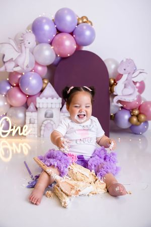 Baby girl in purple tutu smashes first birthday cake. NJ photography studio located in Sussex County NJ. Cake Smash Photographer