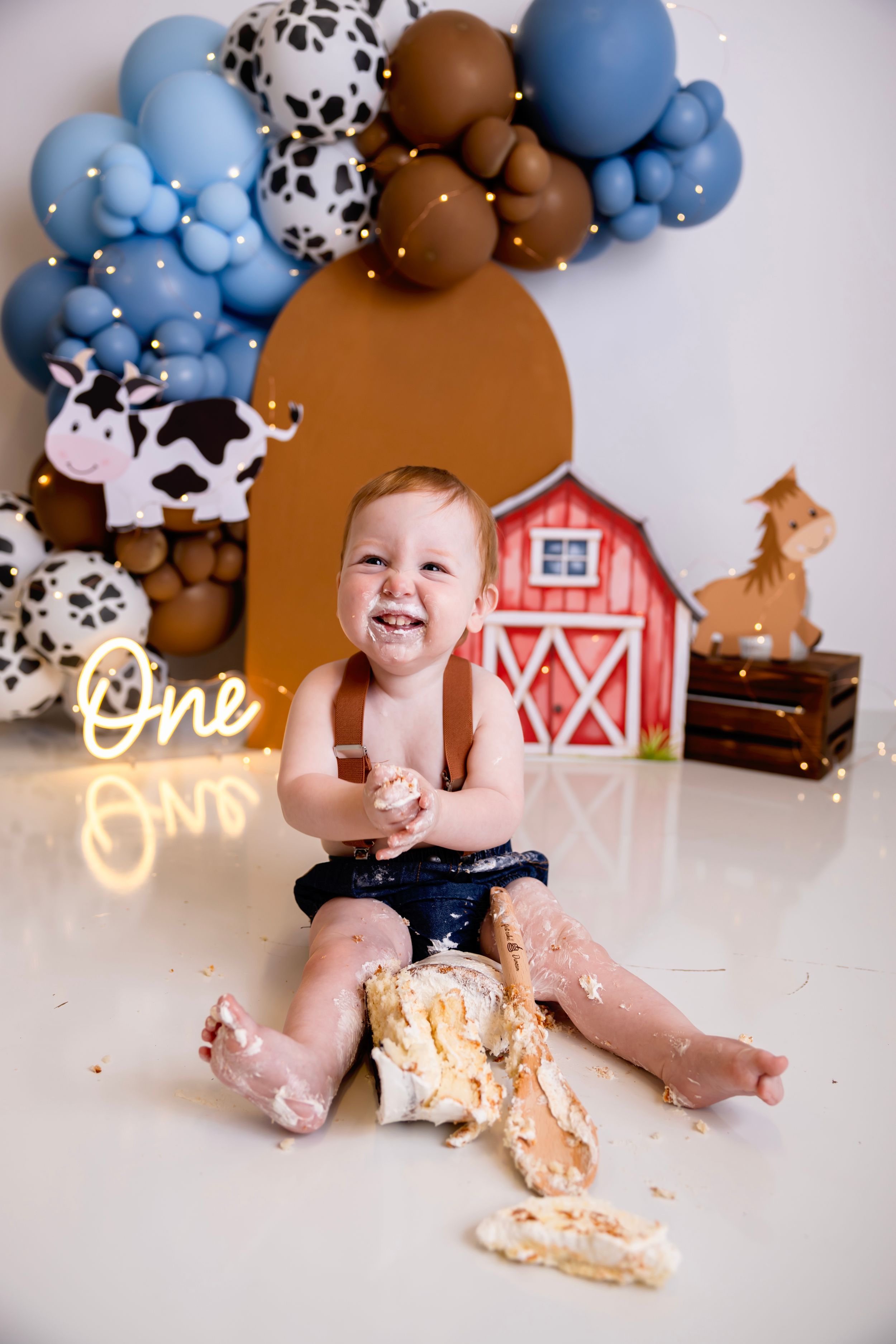Baby's first birthday cake smash with farm theme, balloon arch, barn decor, and cow cutouts. NJ Cake Smash Photographer