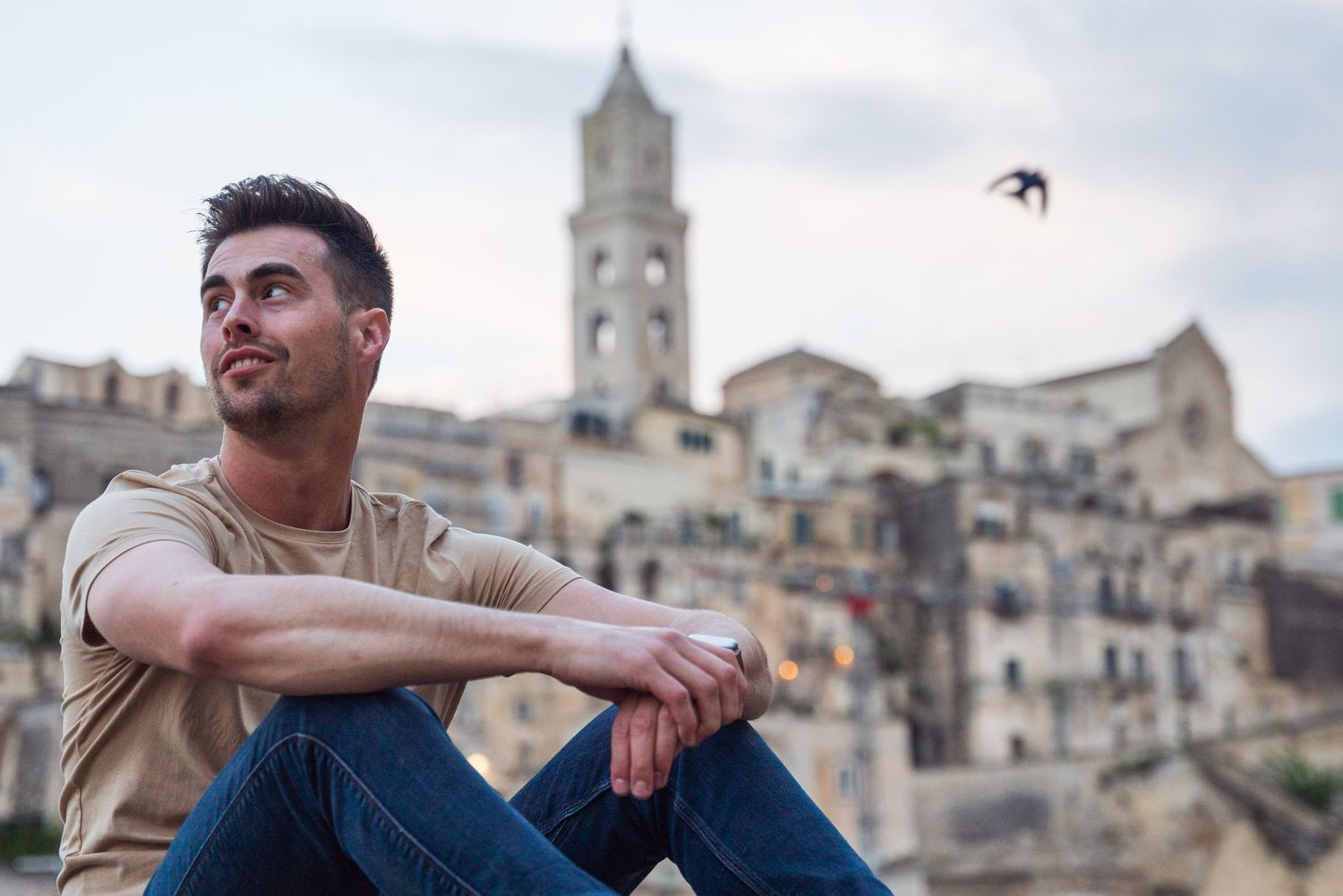 Historic Italian town with bell tower provides backdrop for casual portrait at sunset.