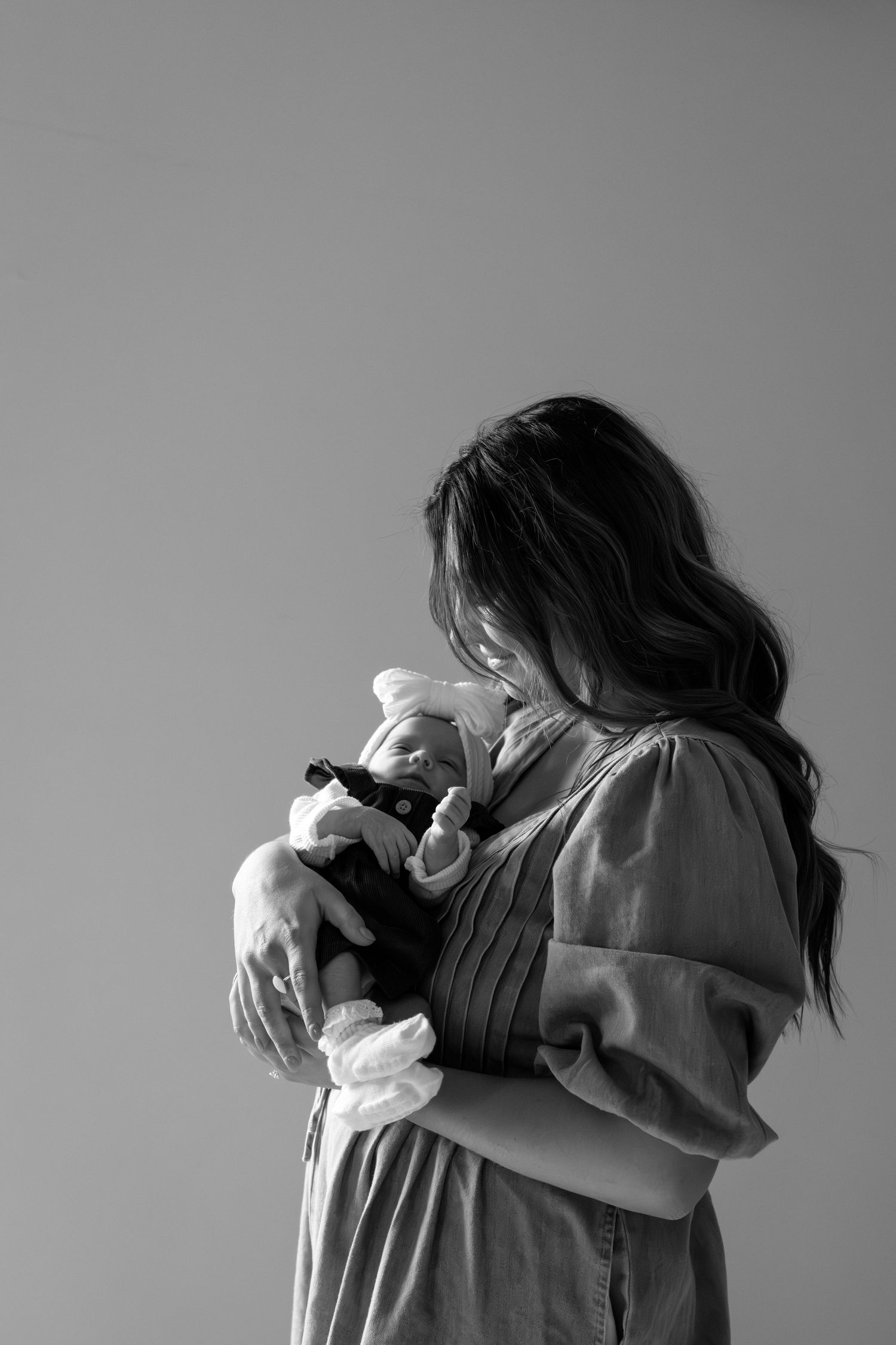 Couple holding ultrasound photos while standing barefoot on grass in romantic announcement shoot.