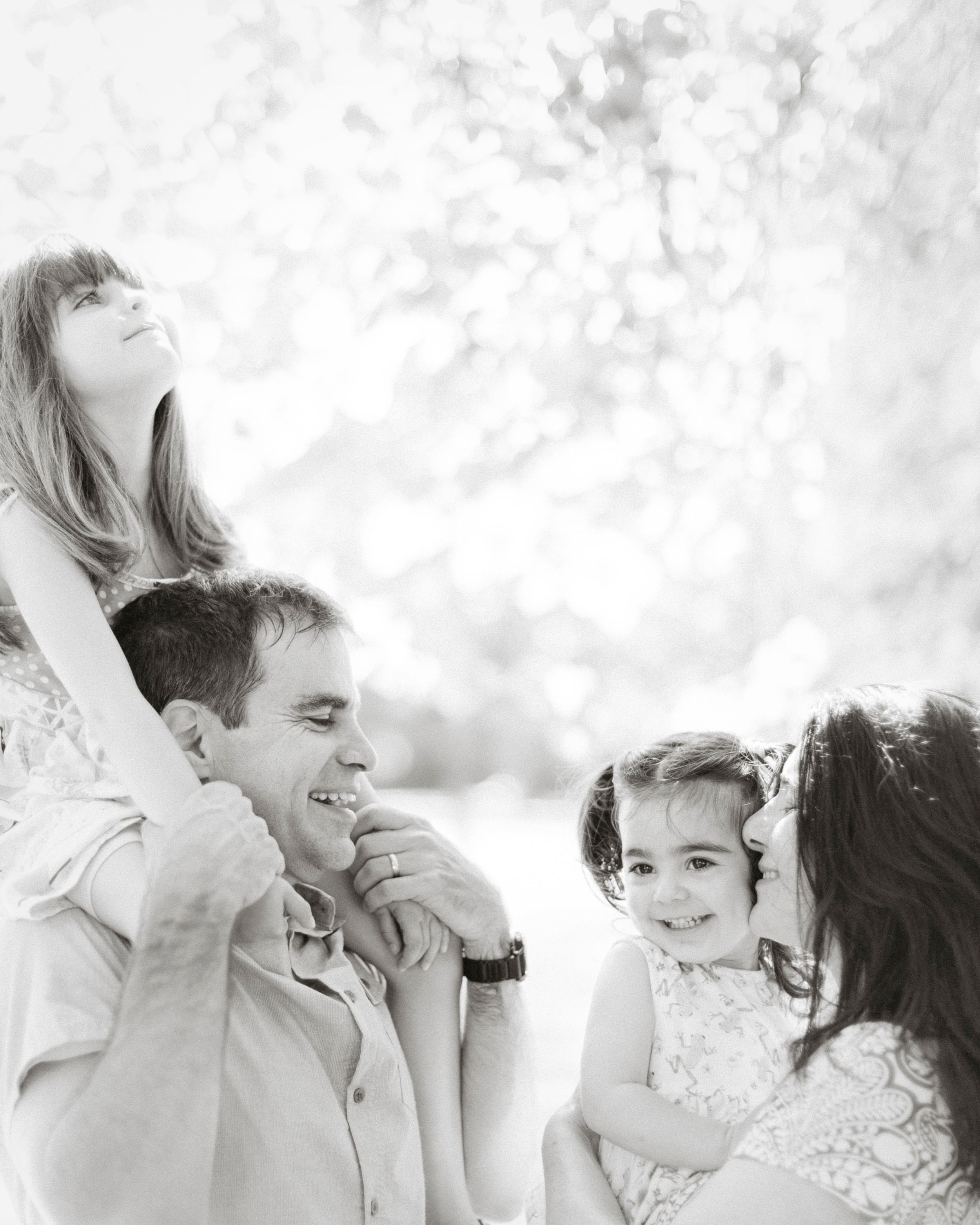 A playful black and white family portrait captured outdoors in natural light.