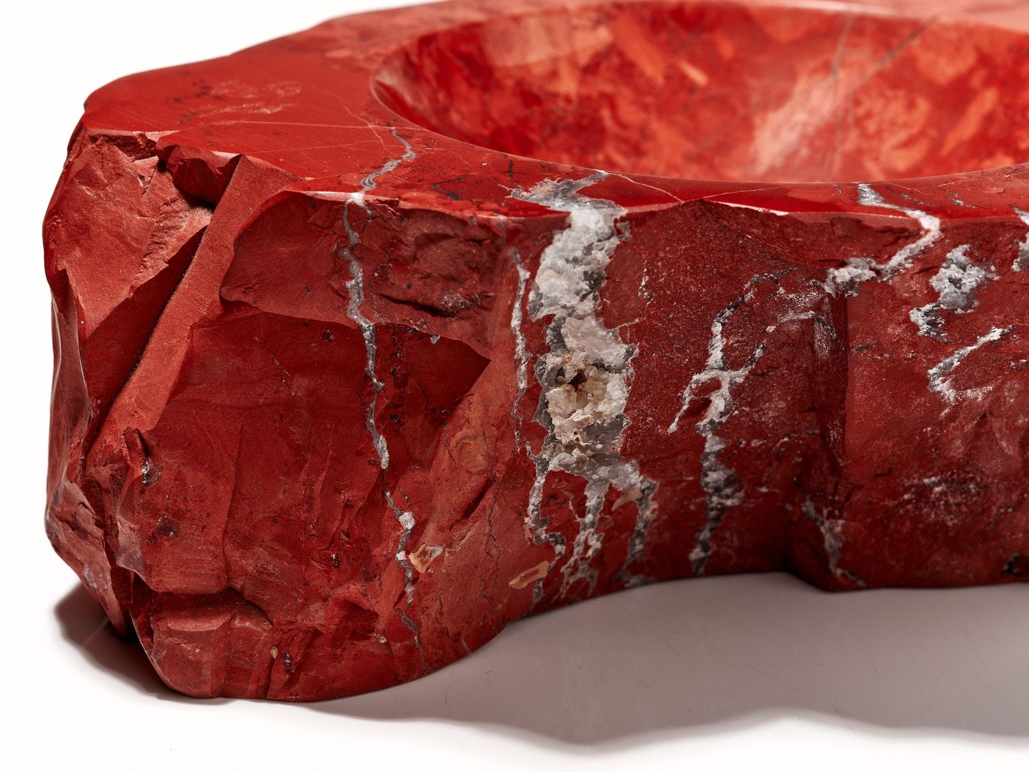 Red marble stone bowl with natural white veining, hand-carved rustic design, decorative centerpiece sculpture.