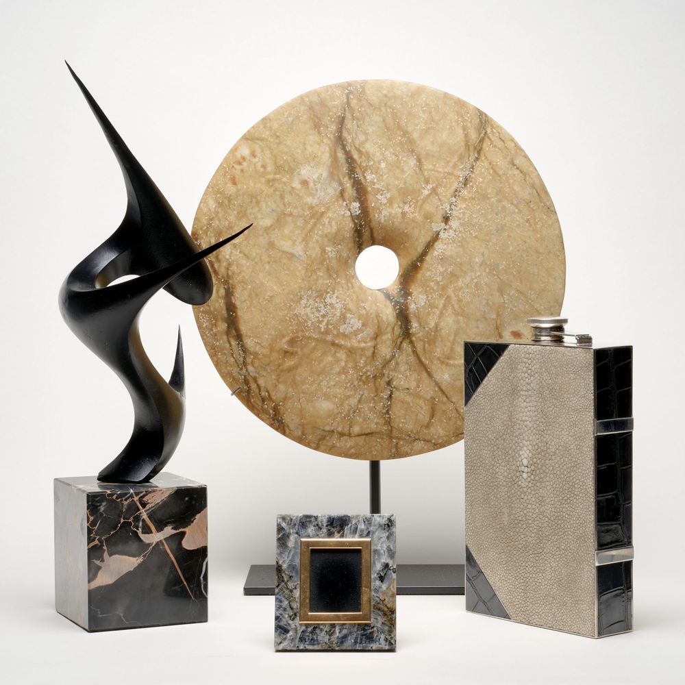 Modern art collection featuring abstract sculpture, stone wheel, and geometric metal objects.