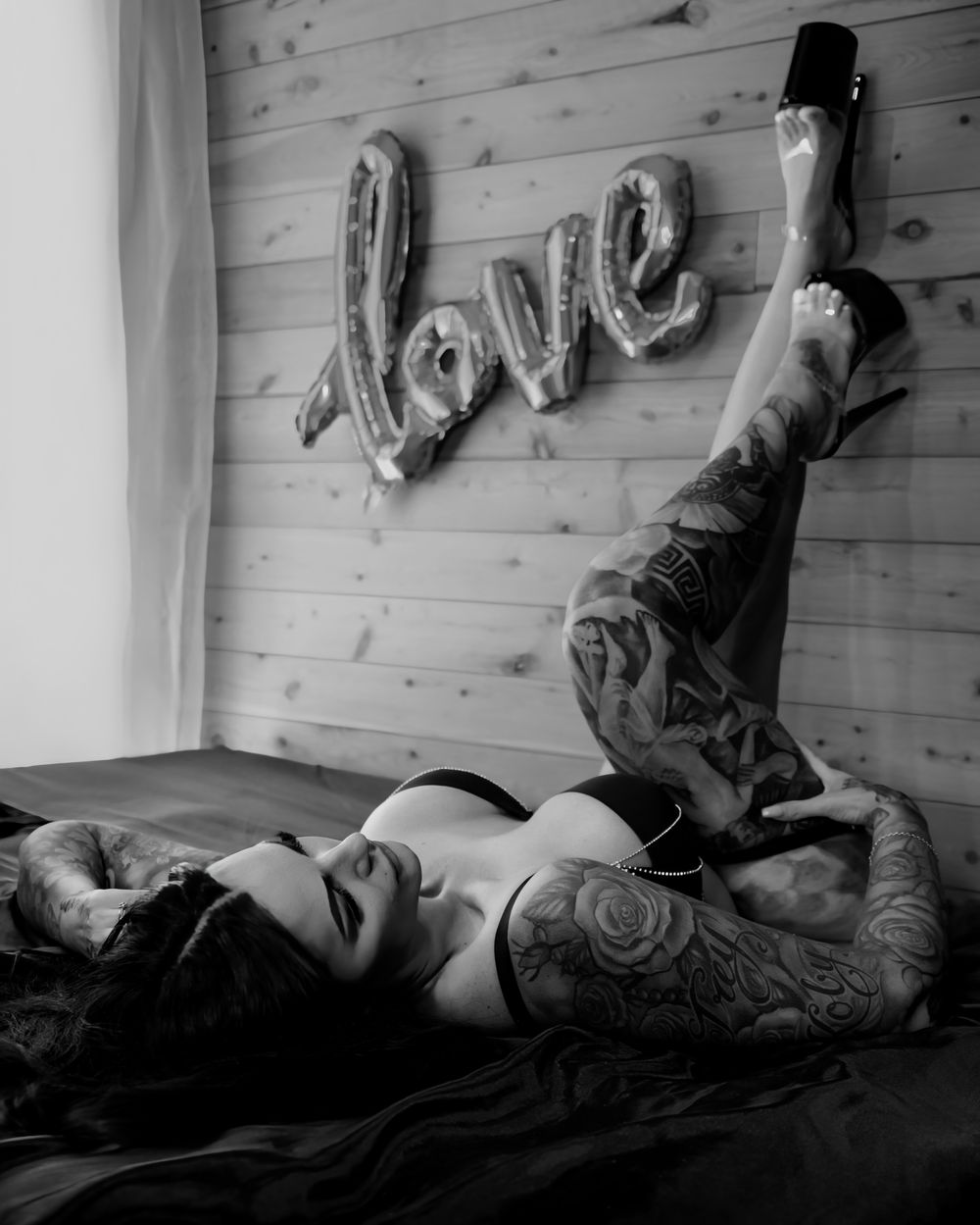 Black and white boudoir photo of tattooed woman posing on bed by Lisha Evans Photography, Brisbane.