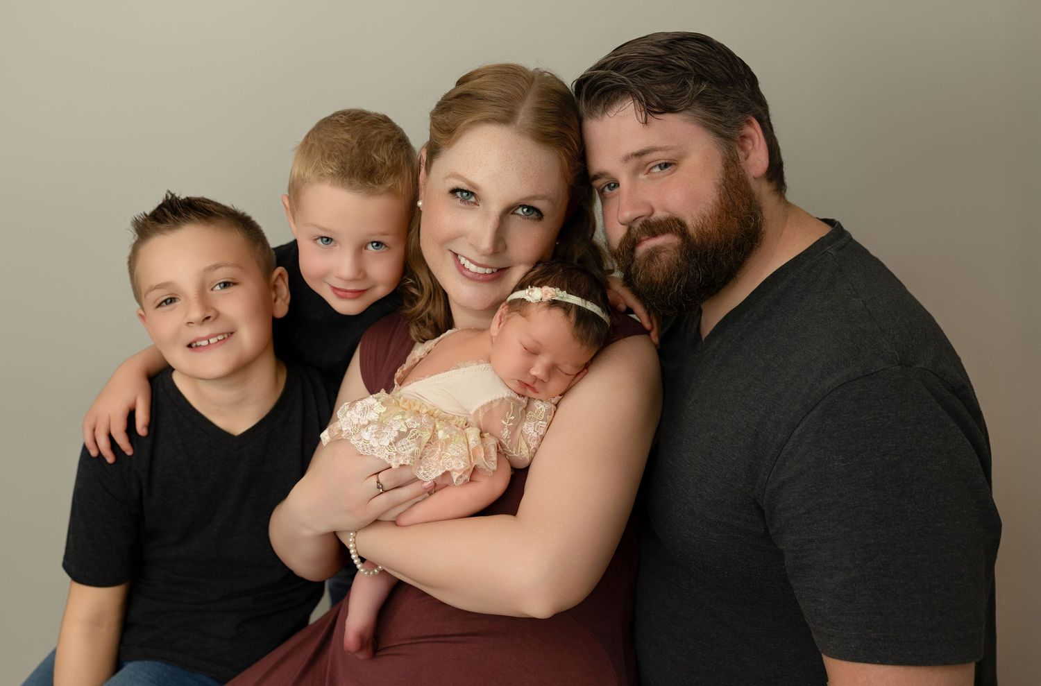 A family portrait with three children and two parents on a neutral studio background.