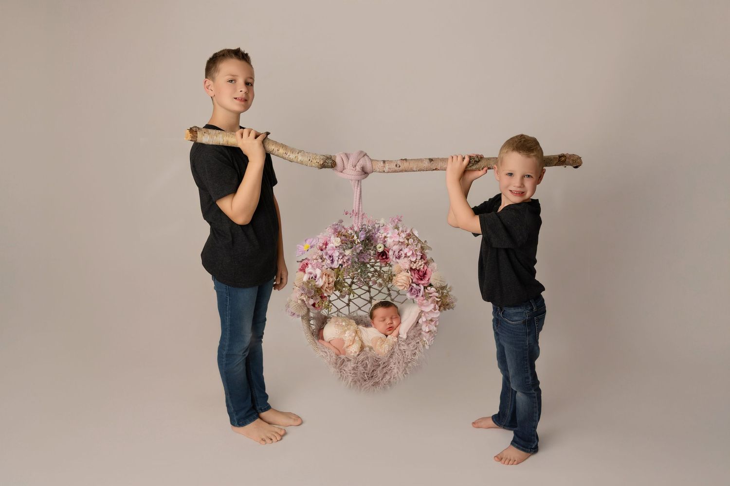 Siblings engaged in a playful dance sequence in a professional photo studio with a neutral gray background.