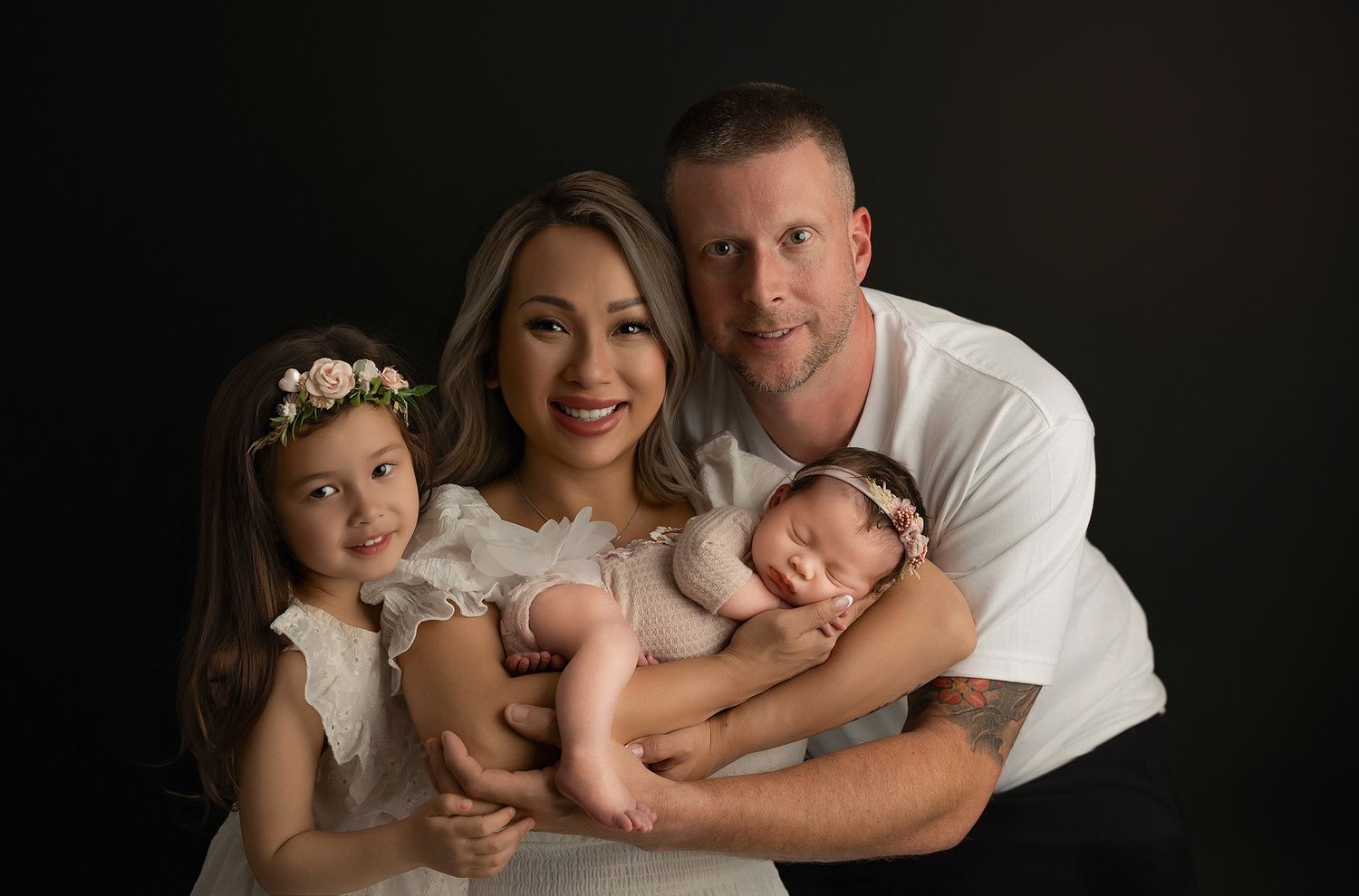Professional black and white newborn photography session showing tender family moments with baby in a studio setting.