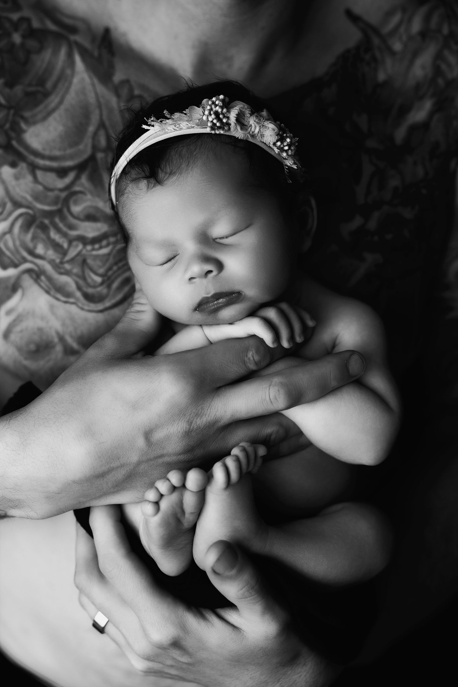 Dramatic black and white close-up photos showing gentle embraces and sleeping infant details.