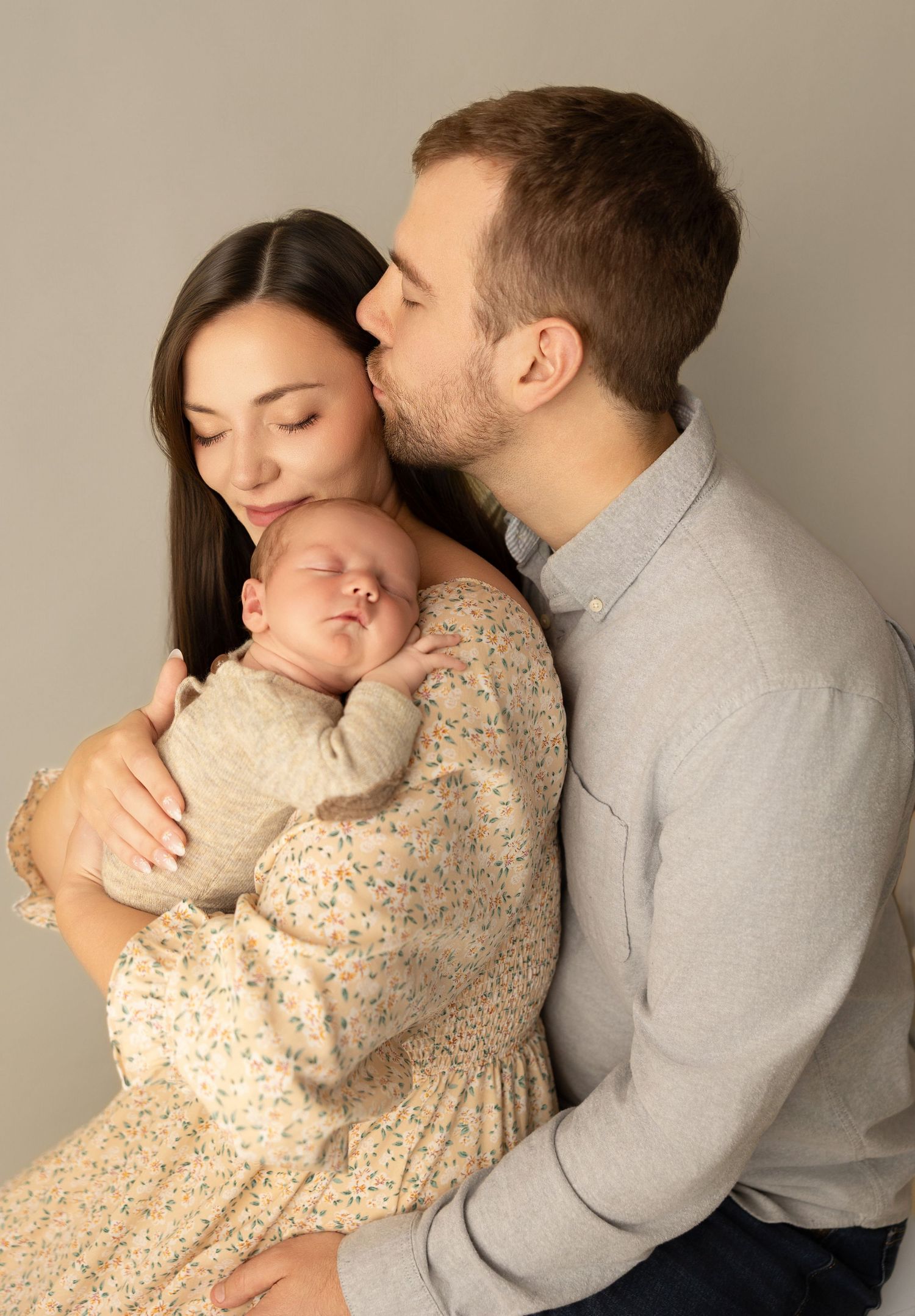 A collection of tender moments between a family and their newborn baby in studio portraits with neutral backgrounds.