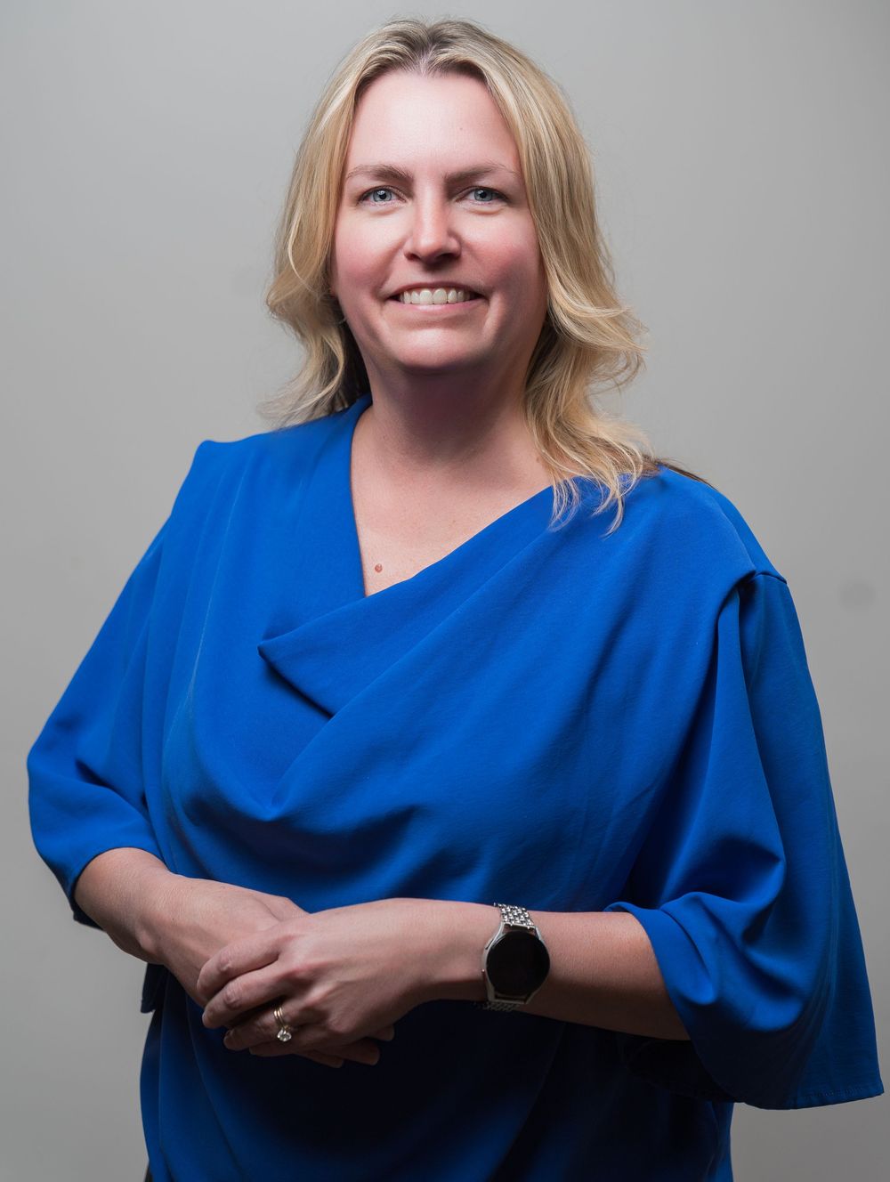 Person in royal blue medical scrubs poses against grey background in progressive sequence of expressions.