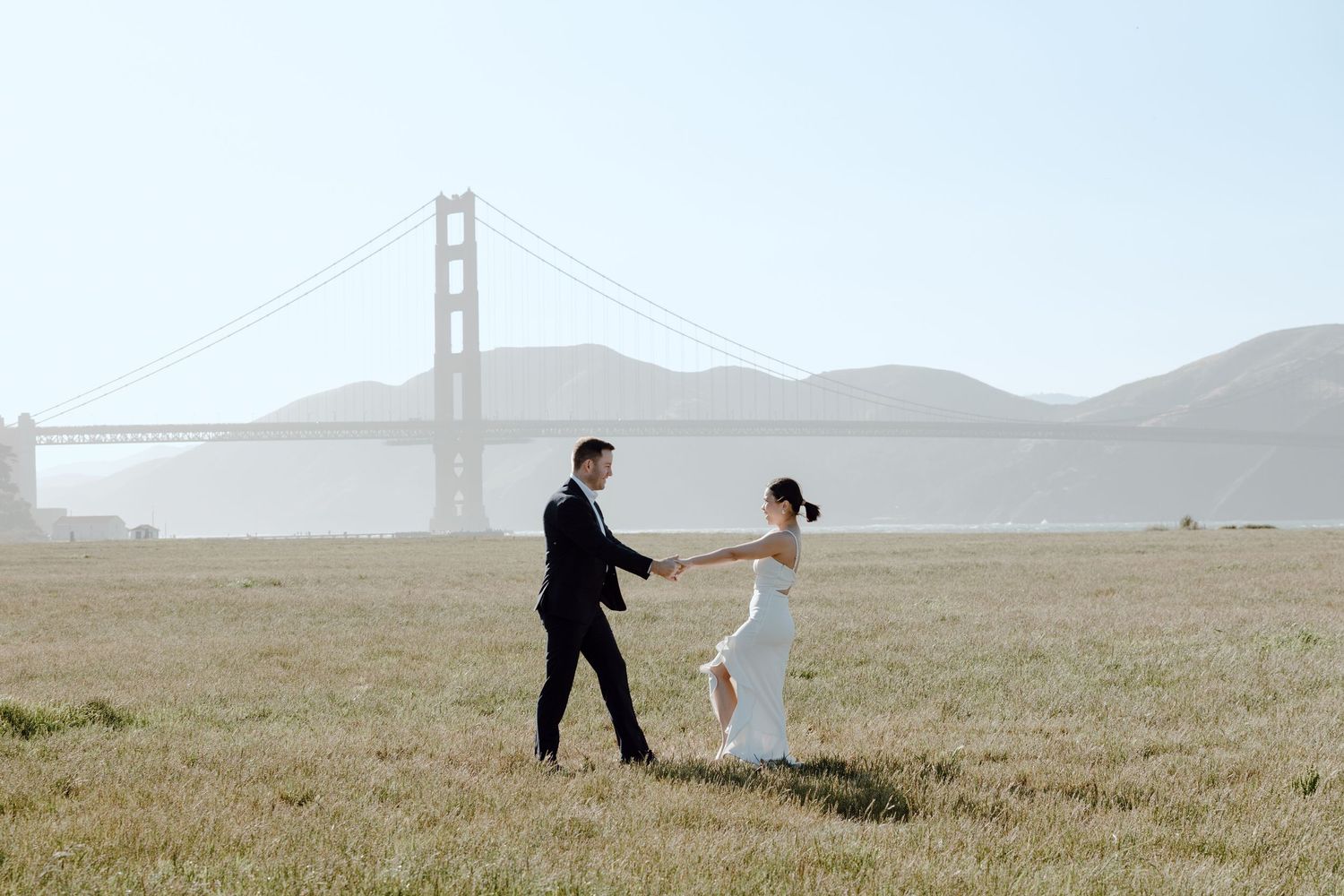 A man proposes to his partner on a cliff overlooking a dramatic coastal landscape at sunset.