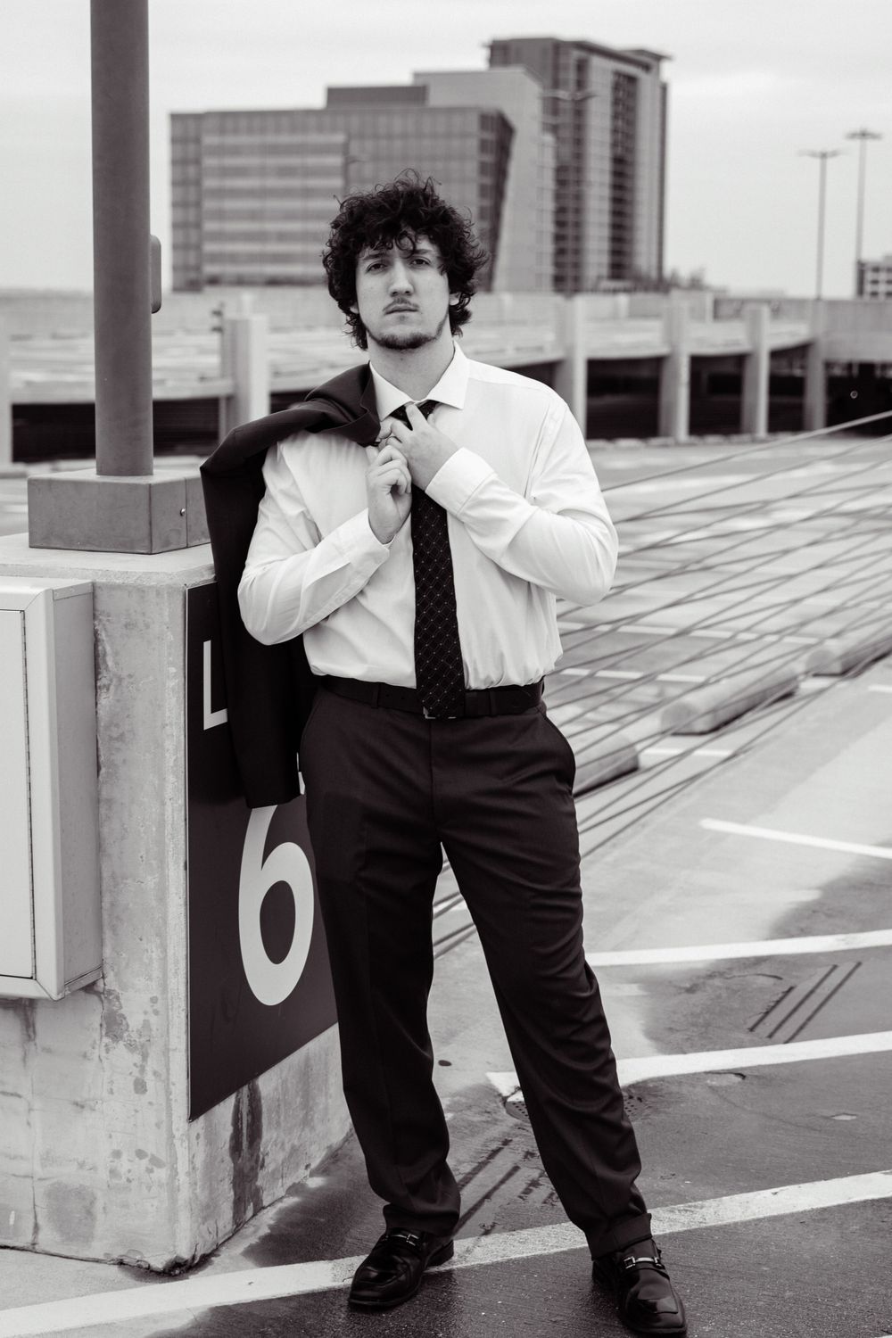 Black and white portrait of person in business attire against parking structure backdrop.