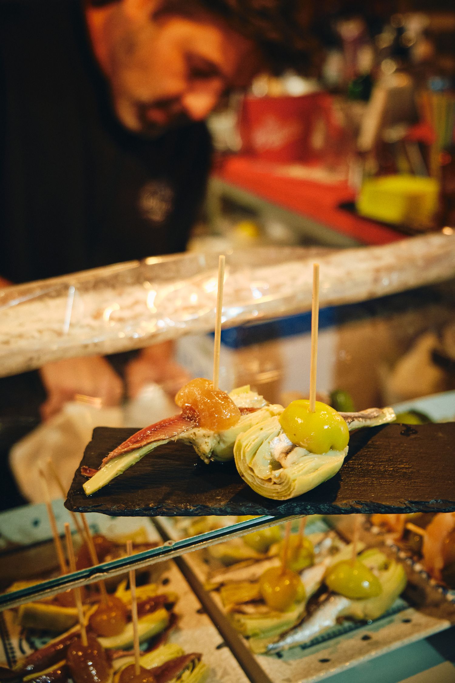 Gourmet tapas dish with artichoke and garnishes served on a black slate board.