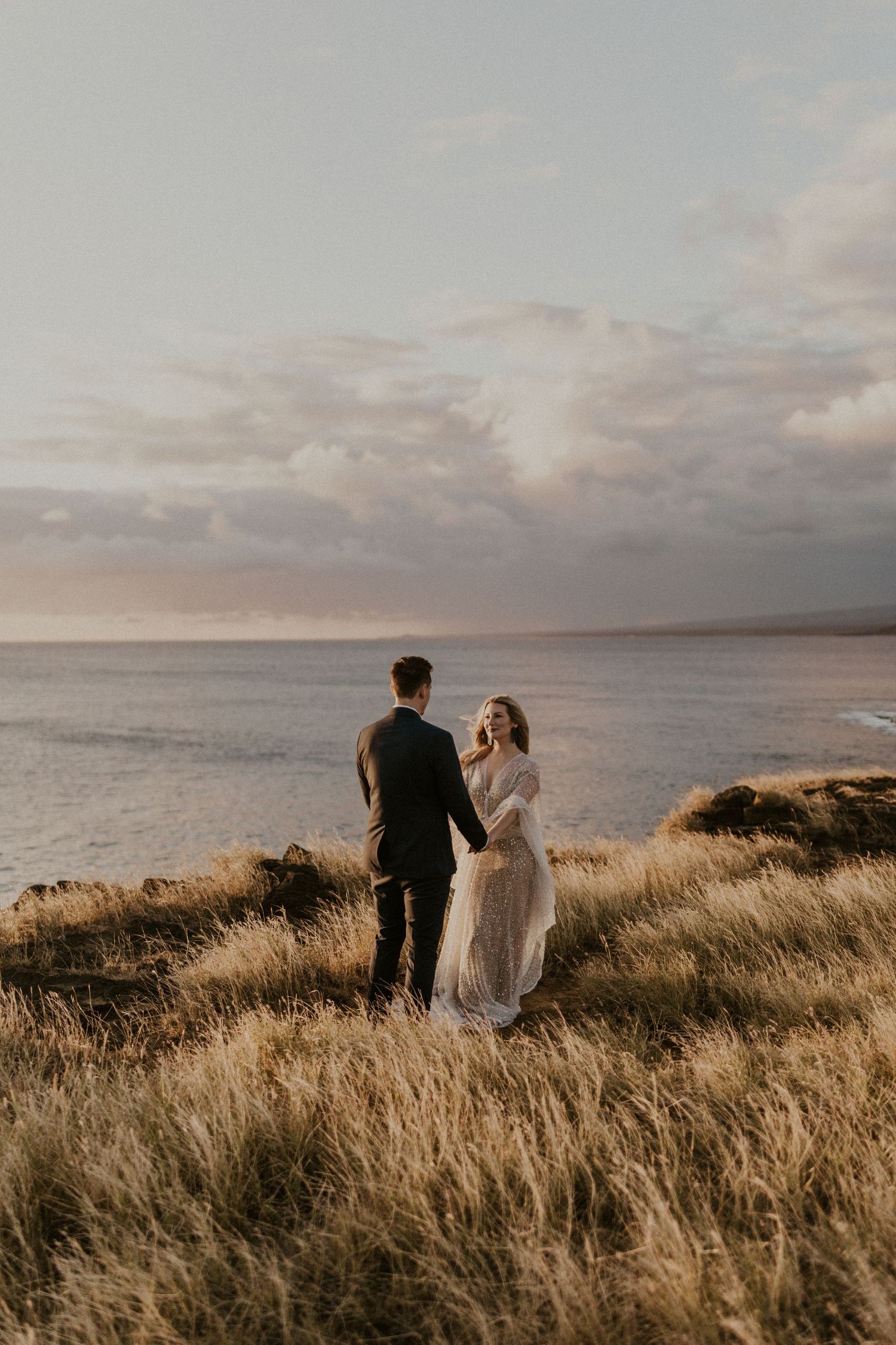 Couple having a wedding ceremony on a cliff overlooking the ocean in Hawaii