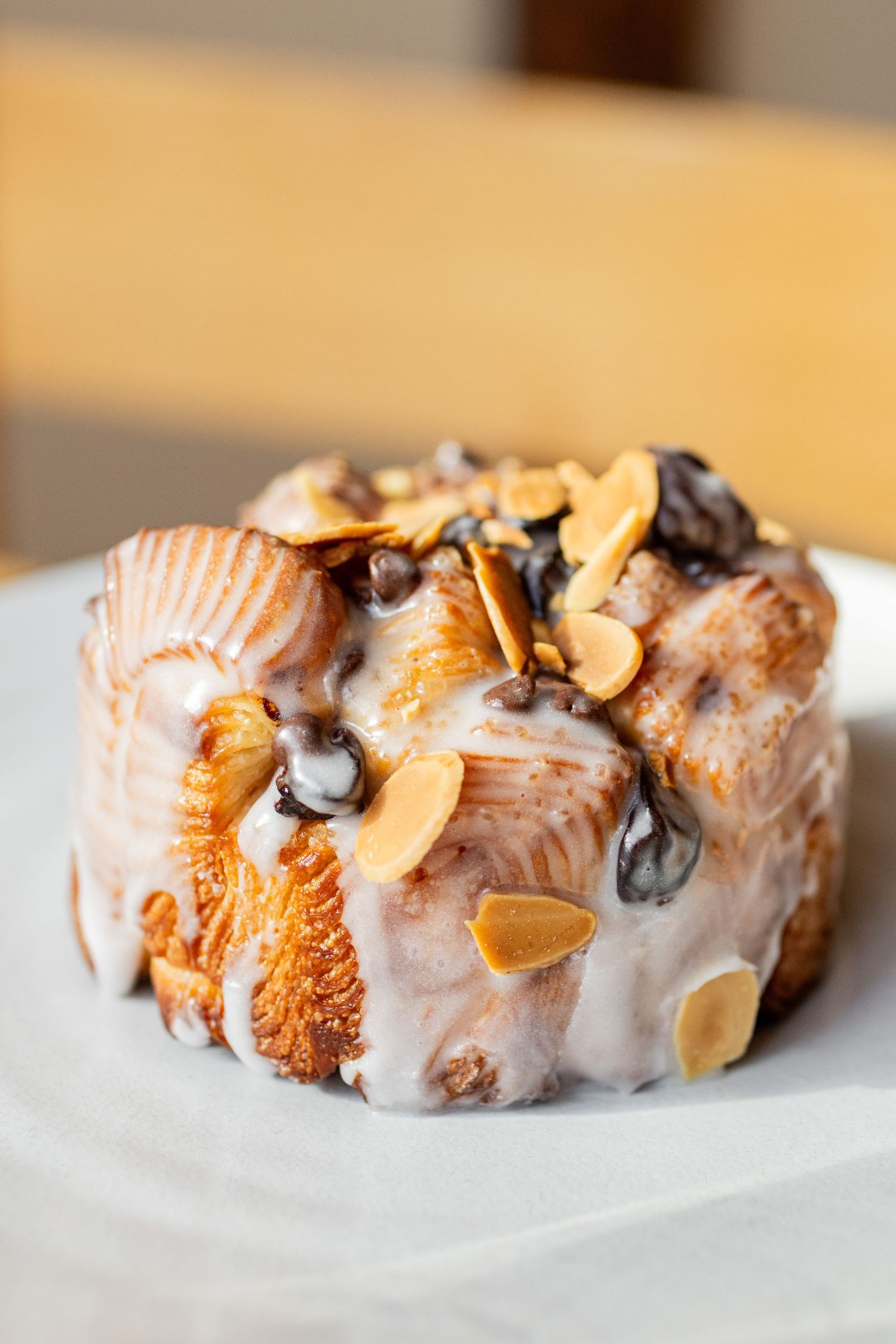 A close-up sequence of glazed pastries with nuts and chocolate drizzle on a white surface.