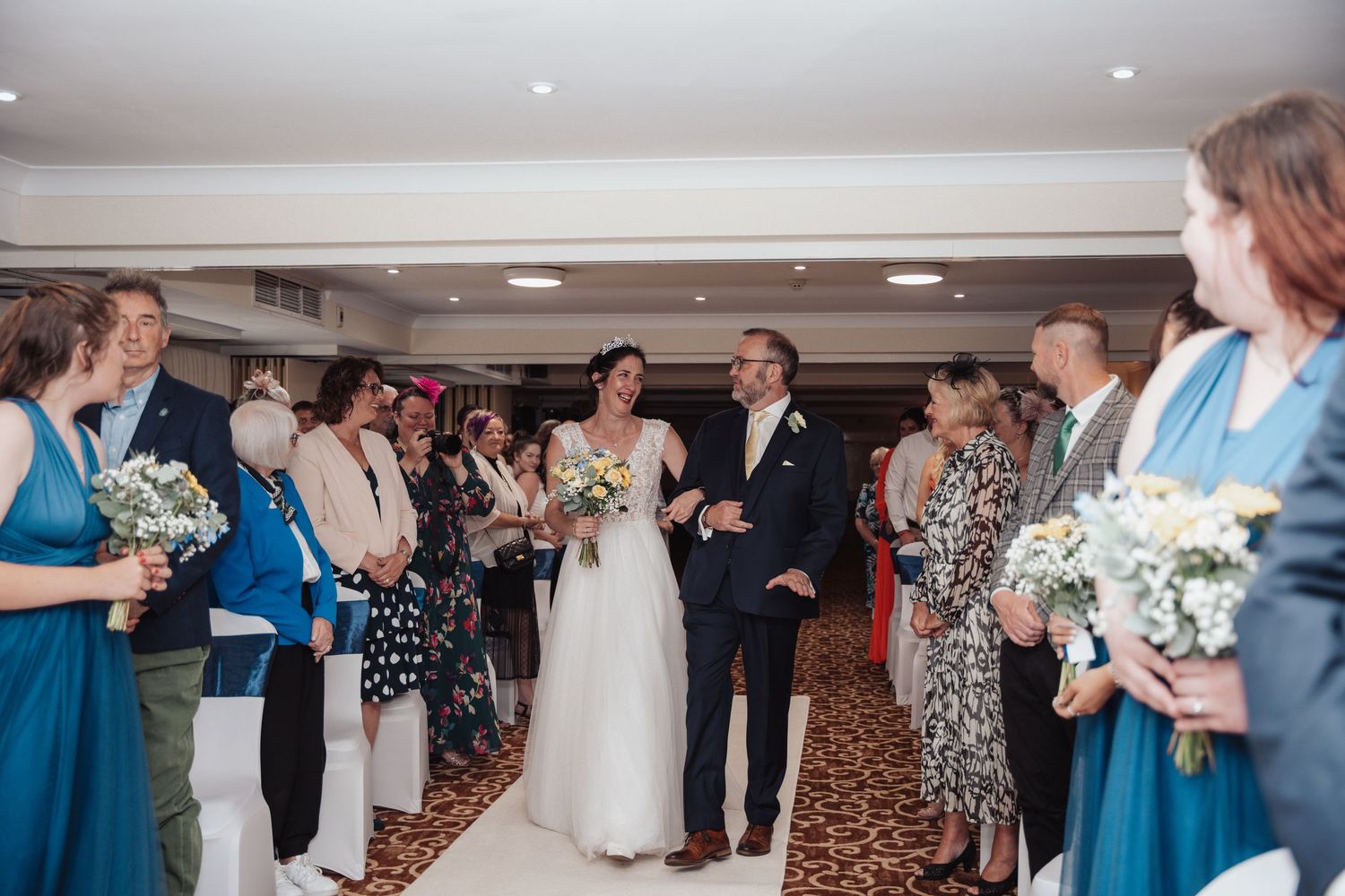 Wedding guests dancing and celebrating together on a dance floor at an indoor reception venue.