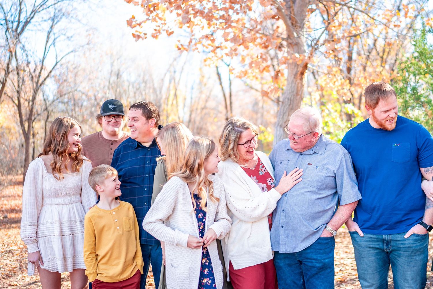 Multi-generational family laughing together outdoors during autumn photoshoot.