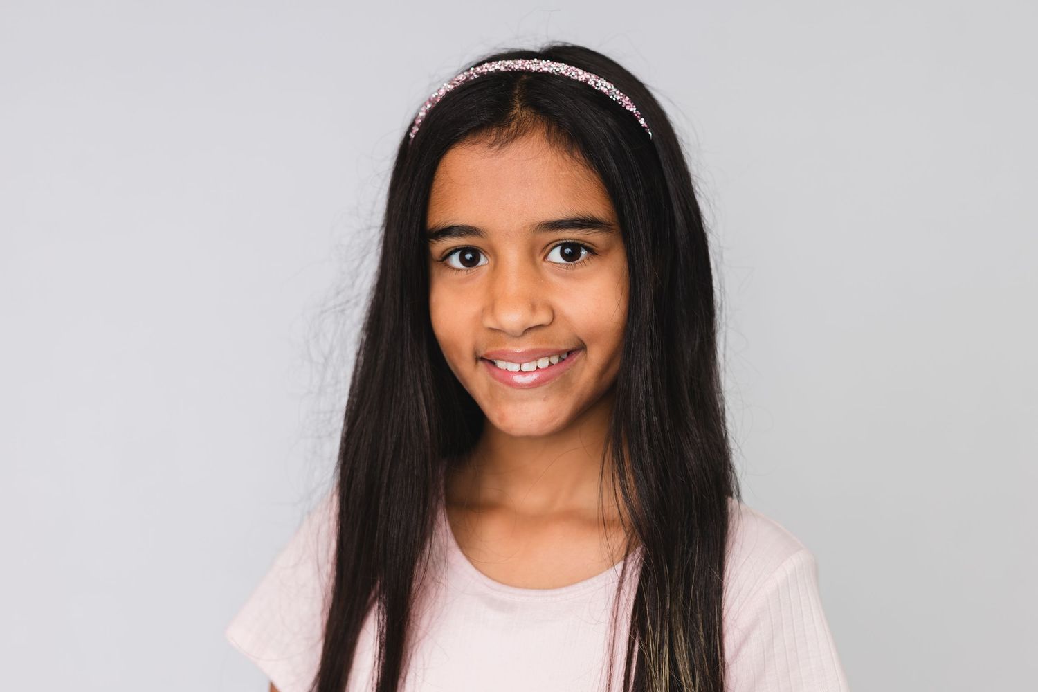 Child wearing a red sweater and hair bows poses for a close-up portrait.