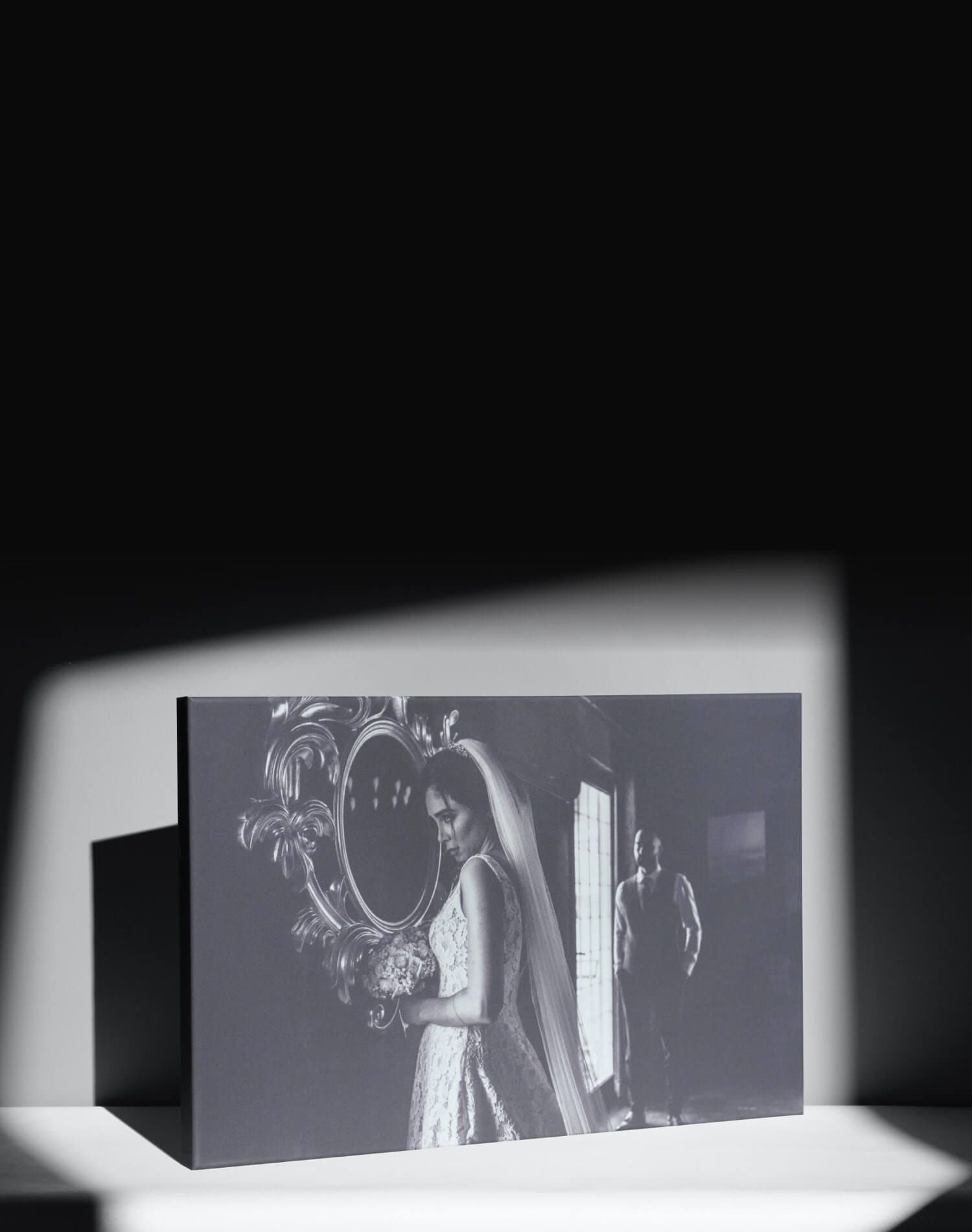 A black and white photograph shown in dramatic lighting with diagonal shadows cast across a displayed image.