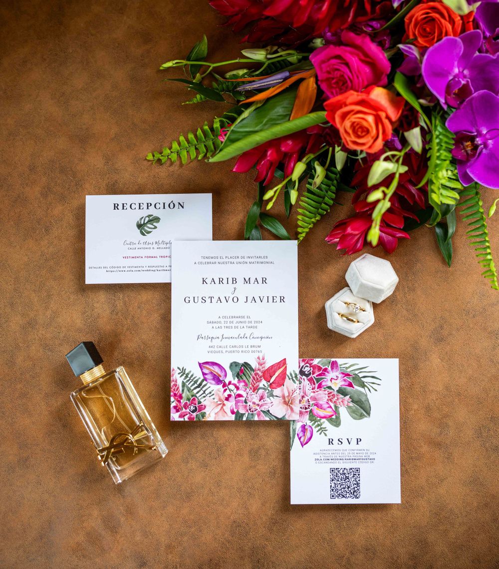Tropical wedding invitation suite with perfume bottle and vibrant floral arrangements.