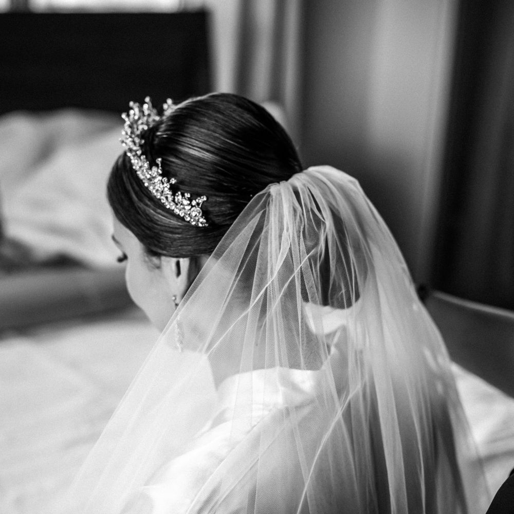 Side profile views of bride wearing lace veil and crystal crown.