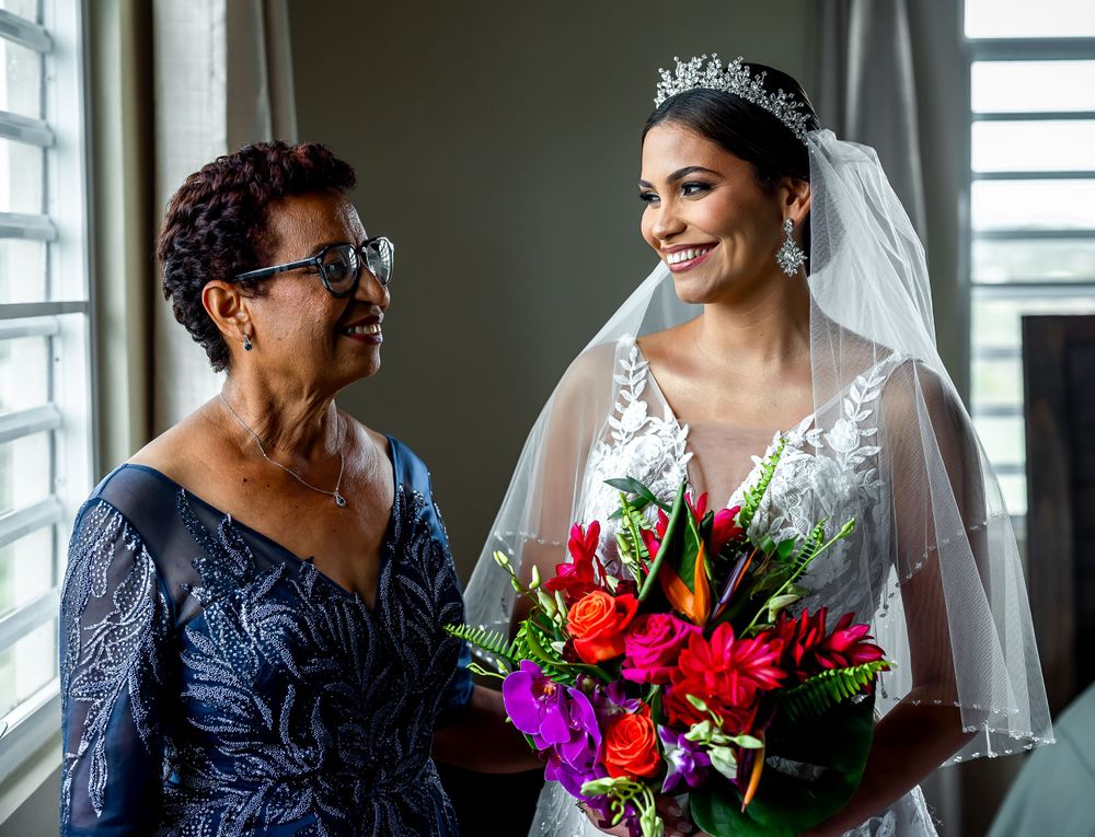 A stunning bridal bouquet featuring vibrant red and purple flowers with lush greenery and a flowing white veil.