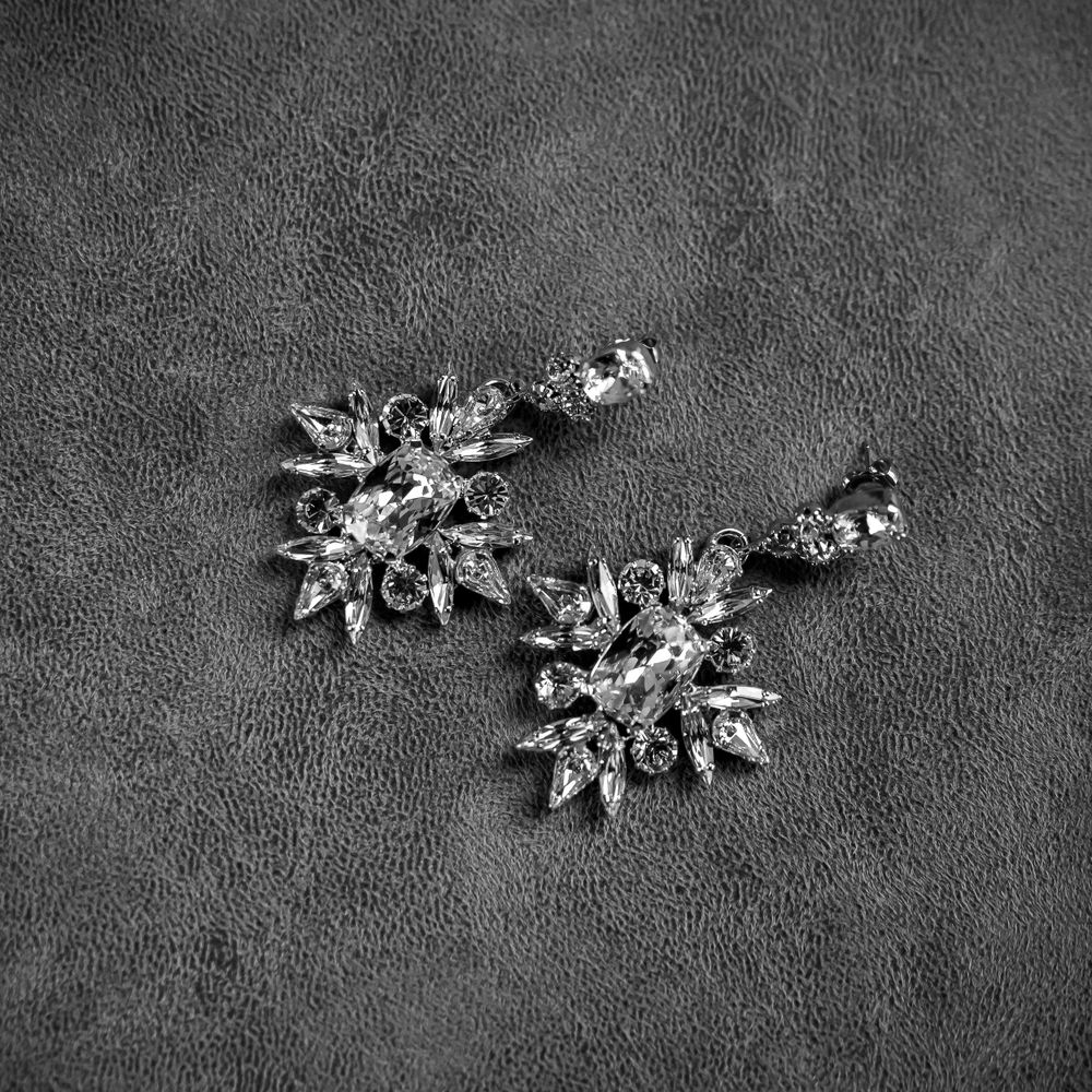 Vintage-inspired crystal snowflake earrings on dark textured background.