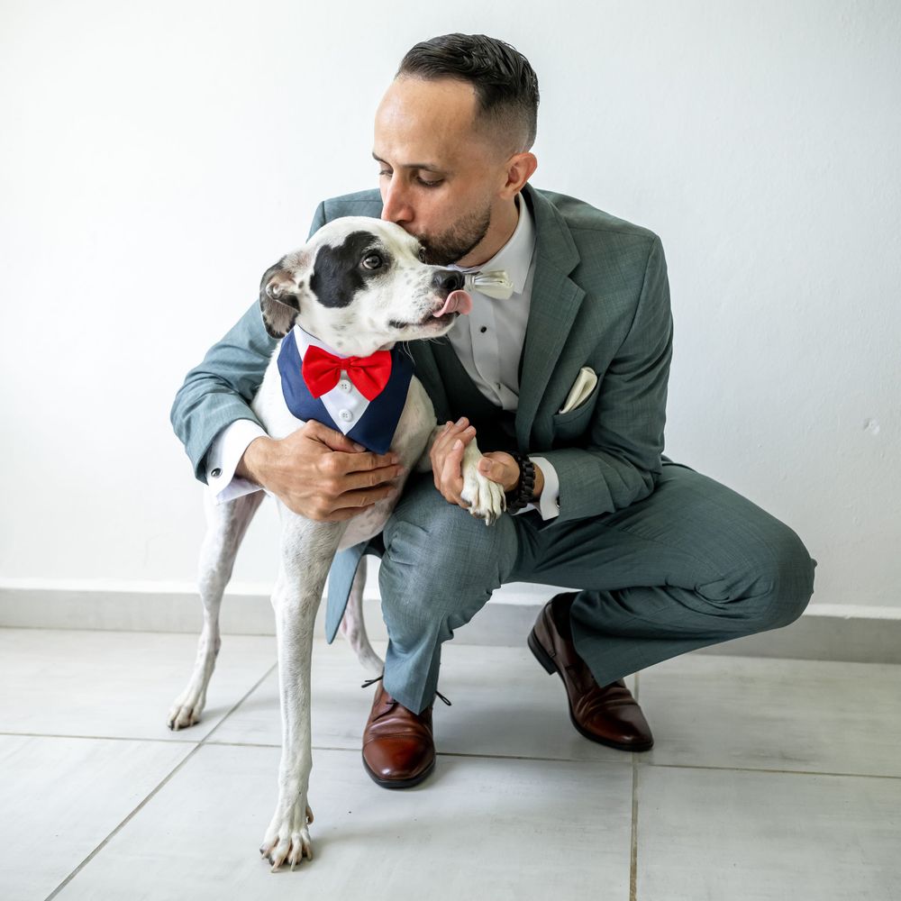 A dressed-up person posing with their dog wearing matching formal attire.