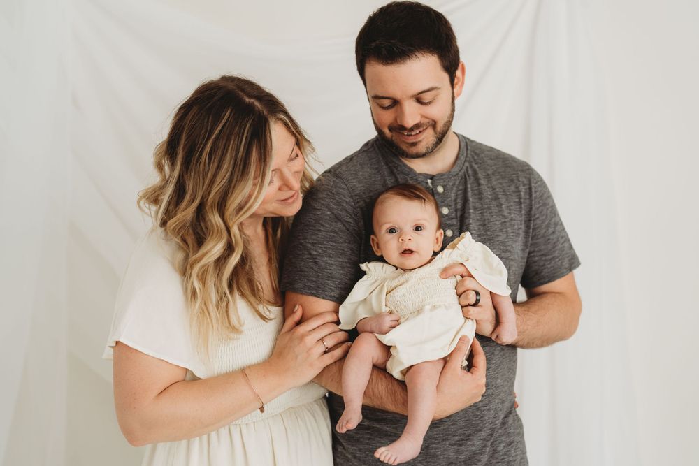 Family photo against white background showing tender moment with baby.