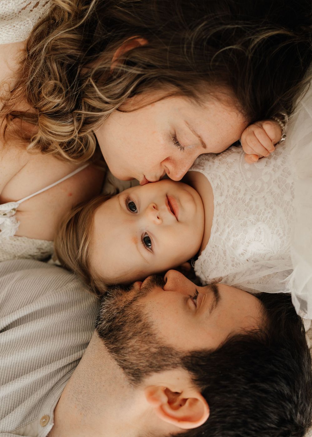 An intimate family portrait showing tender affection and closeness against a light background.