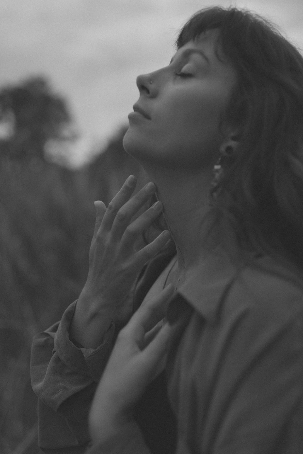 A black and white portrait of someone in profile with eyes closed in a peaceful, contemplative pose against a blurred background.