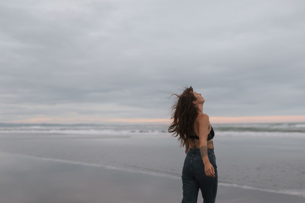 A series of beach photos showing someone with windswept hair enjoying the misty oceanfront at sunset.