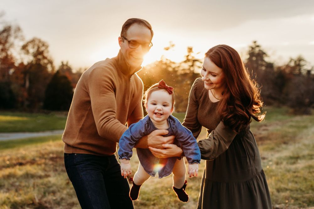 Family enjoying a playful moment together at sunset in a grassy field.