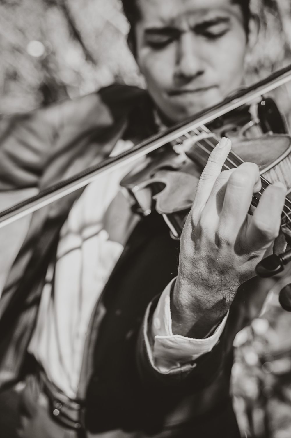 Black and white close-up of hands playing a violin with artistic focus.