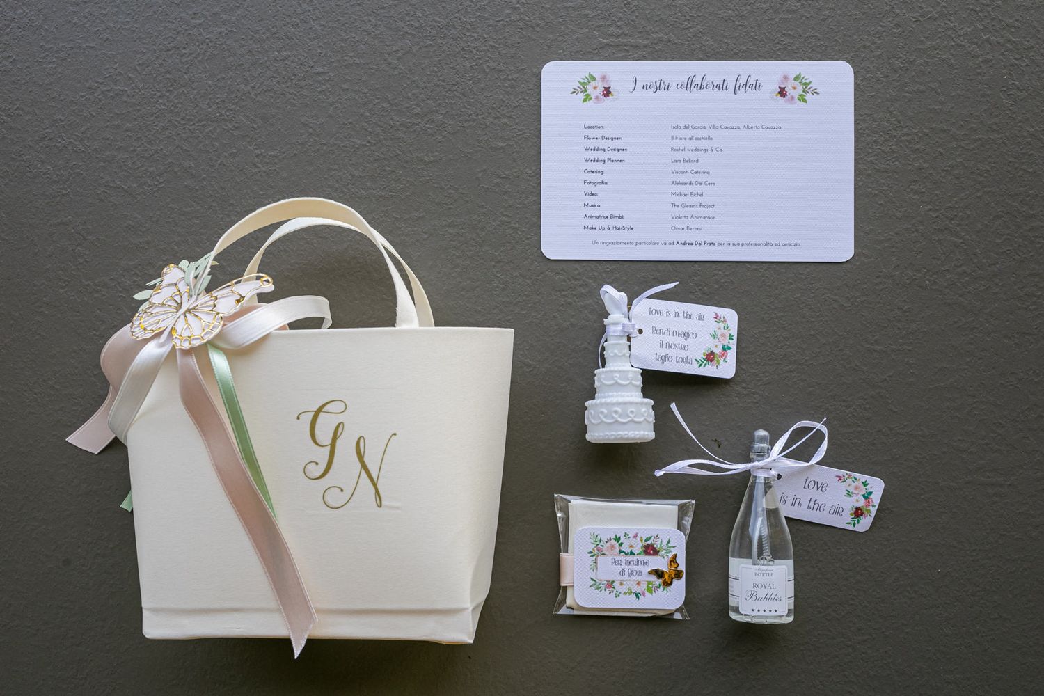 Wedding accessories and gift bags arranged on a dark surface.