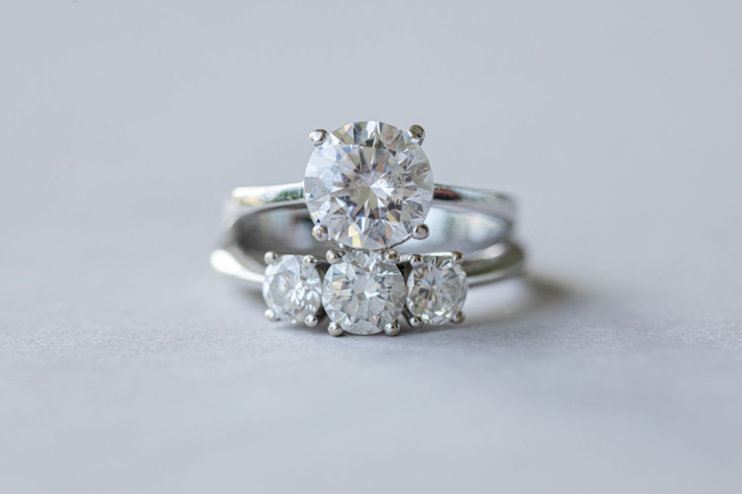 Close-up of sparkling diamond engagement ring on white surface.