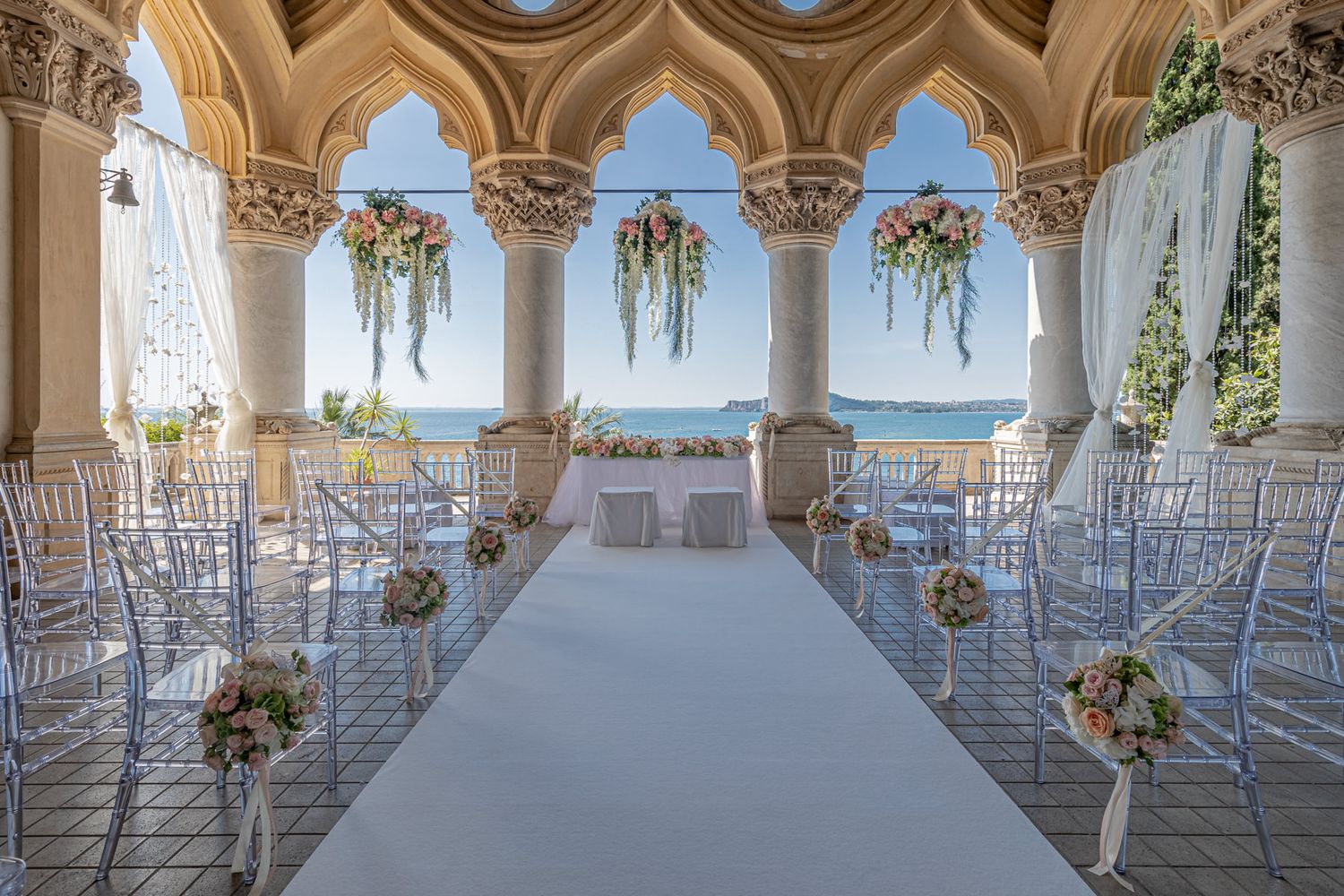 Elegant wedding venue with ornate columns and white chairs set up for ceremony.