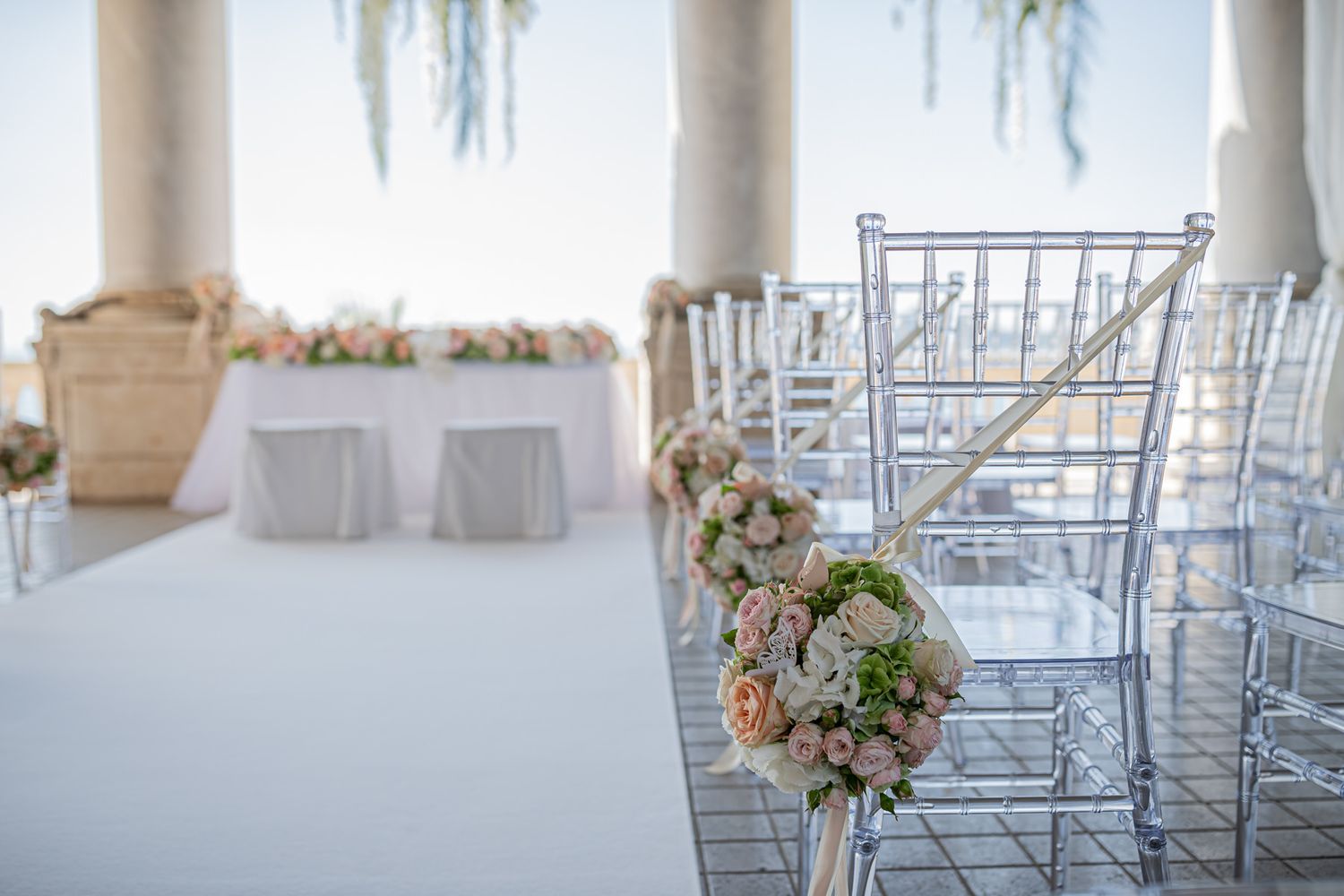 White chairs arranged in rows at an elegant indoor wedding ceremony space.