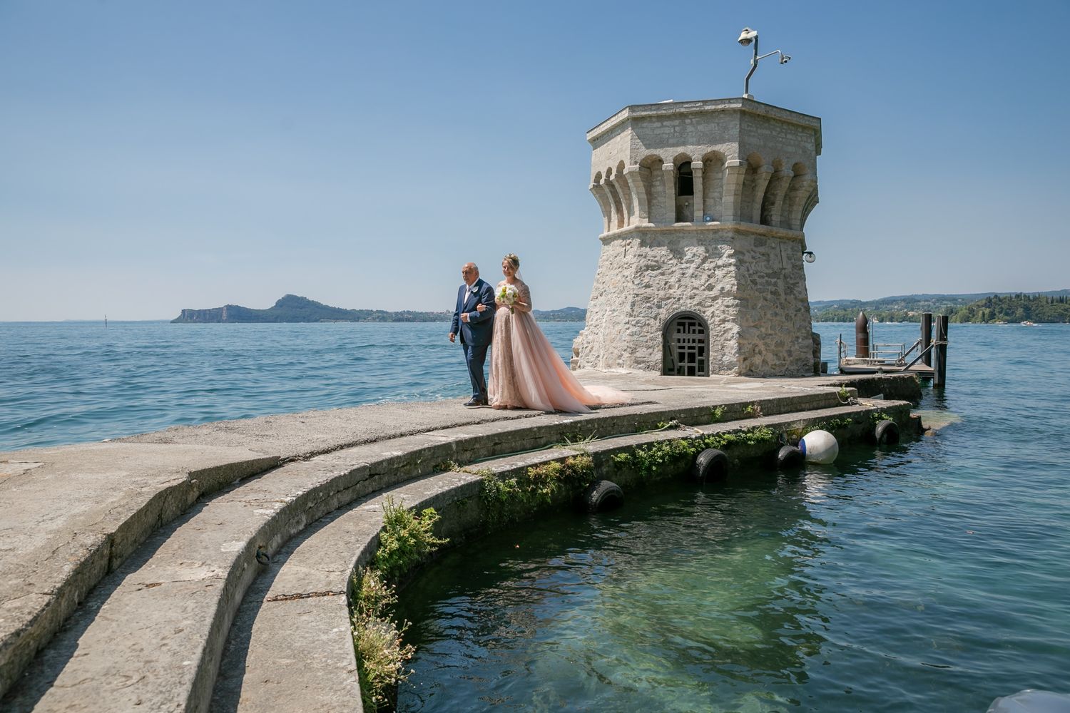 A scenic waterfront wedding venue with a stone lighthouse and pier overlooking the ocean.