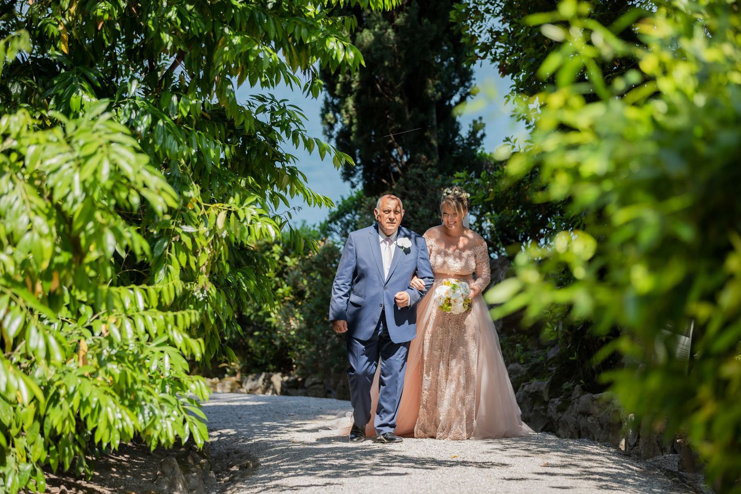 A wedding ceremony procession walking through a lush garden pathway.