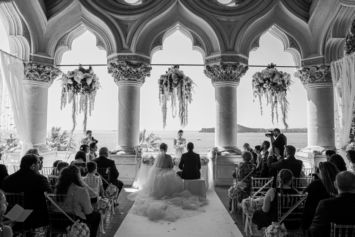 An elegant arched colonnade decorated with floral arrangements for a wedding ceremony.