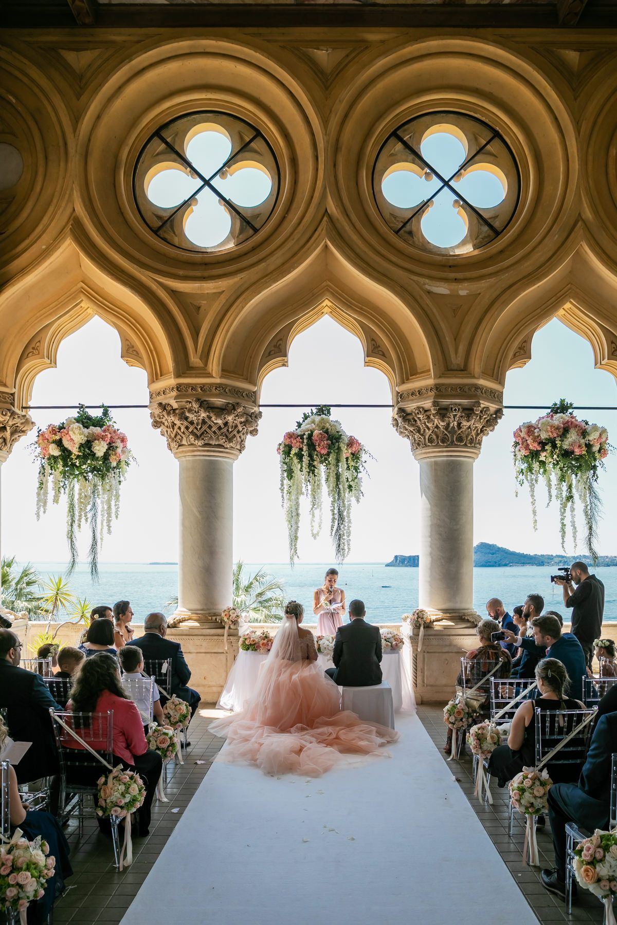 A Mediterranean-style wedding venue with ornate arched columns overlooking the sea.