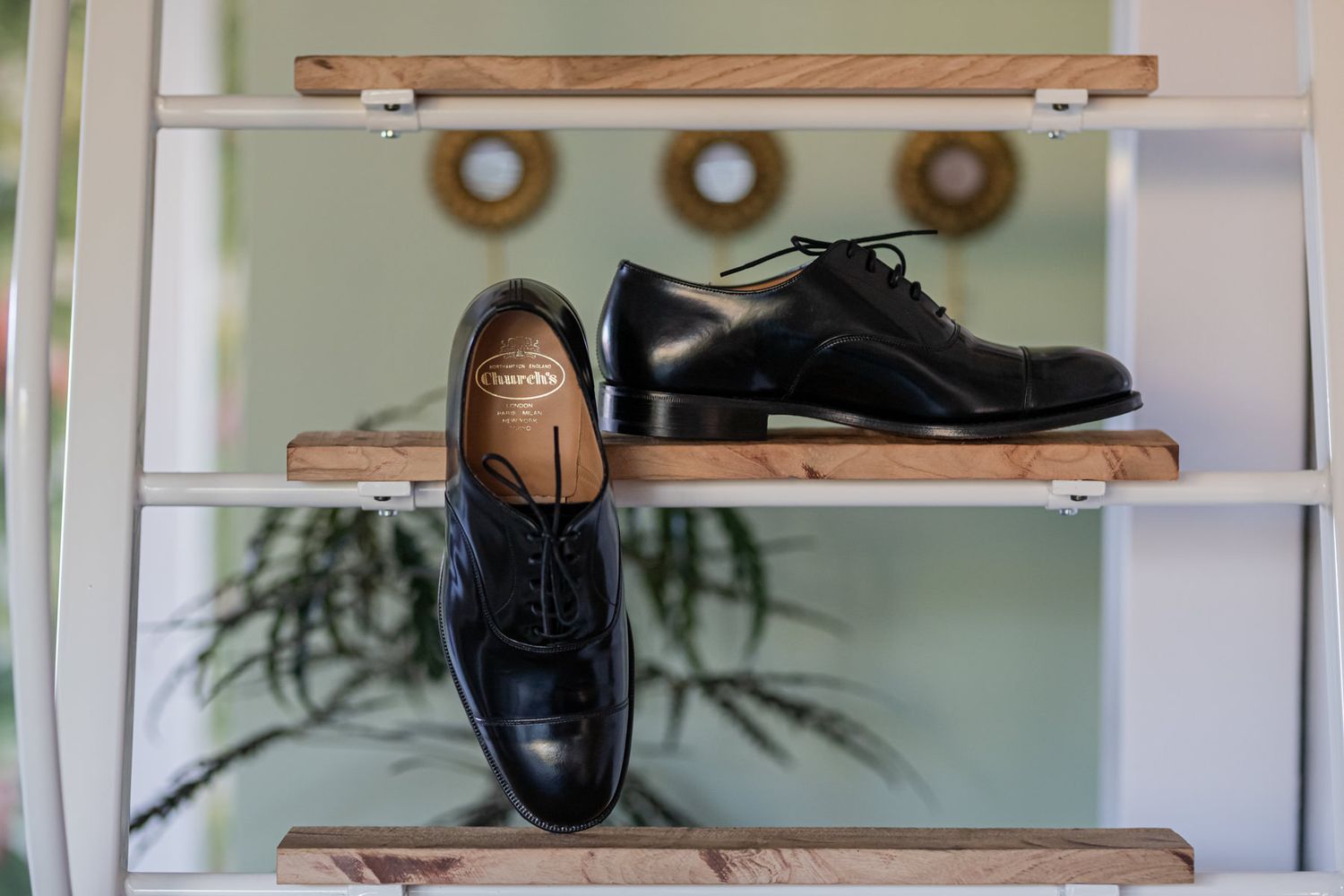 Men's formal shoes and accessories displayed on wooden shelving.