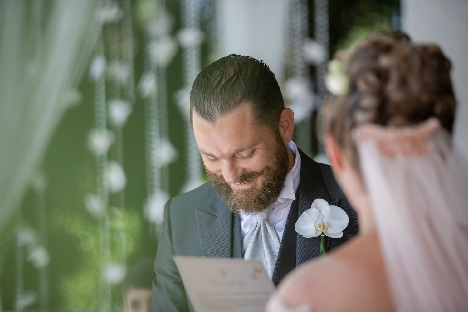 Romantic wedding ceremony moment captured in natural light with greenery backdrop.